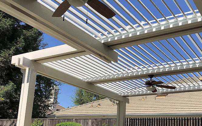 White pergola with ceiling fan creates a shaded oasis on a sunny patio.