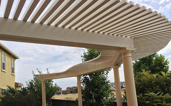A white pergola with open lattice creates shade and adds character to a sunny patio.