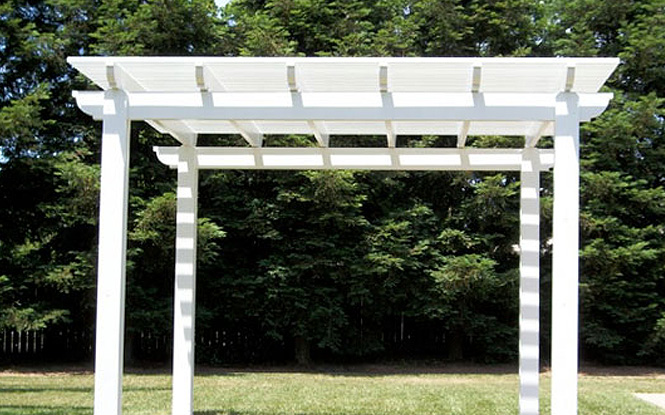 A white pergola casts a cool shadow over a vibrant green field.