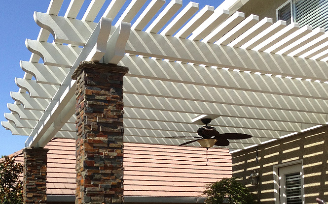 A white vinyl pergola with a ceiling fan provides shade and comfort for a patio.