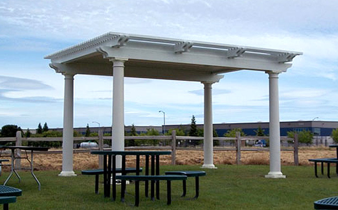 A white pergola creates a striking contrast against a backdrop of lush green grass.