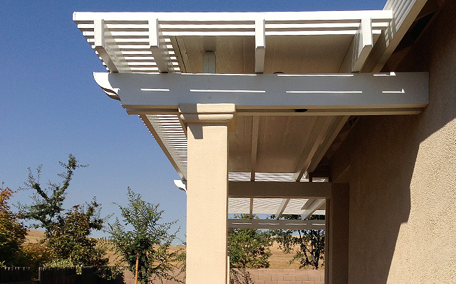 A white pergola shades a cozy sunny patio.